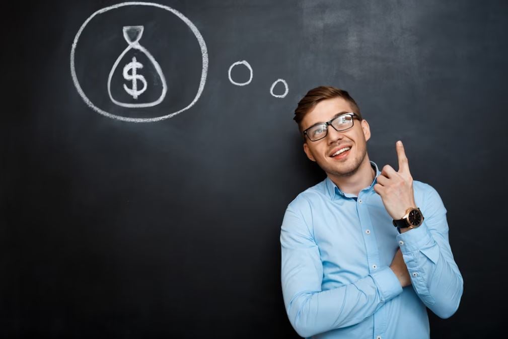 Tesouro direto: homem jovem em frente a lousa, com desenho de saco de dinheiro atrás dele