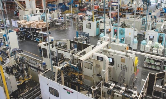 Vista de uma linha de produção industrial automatizada em uma fábrica, com diversos equipamentos e máquinas operacionais.