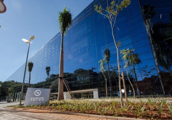 Fachada espelhada da sede da Totvs com palmeiras e céu azul ao fundo