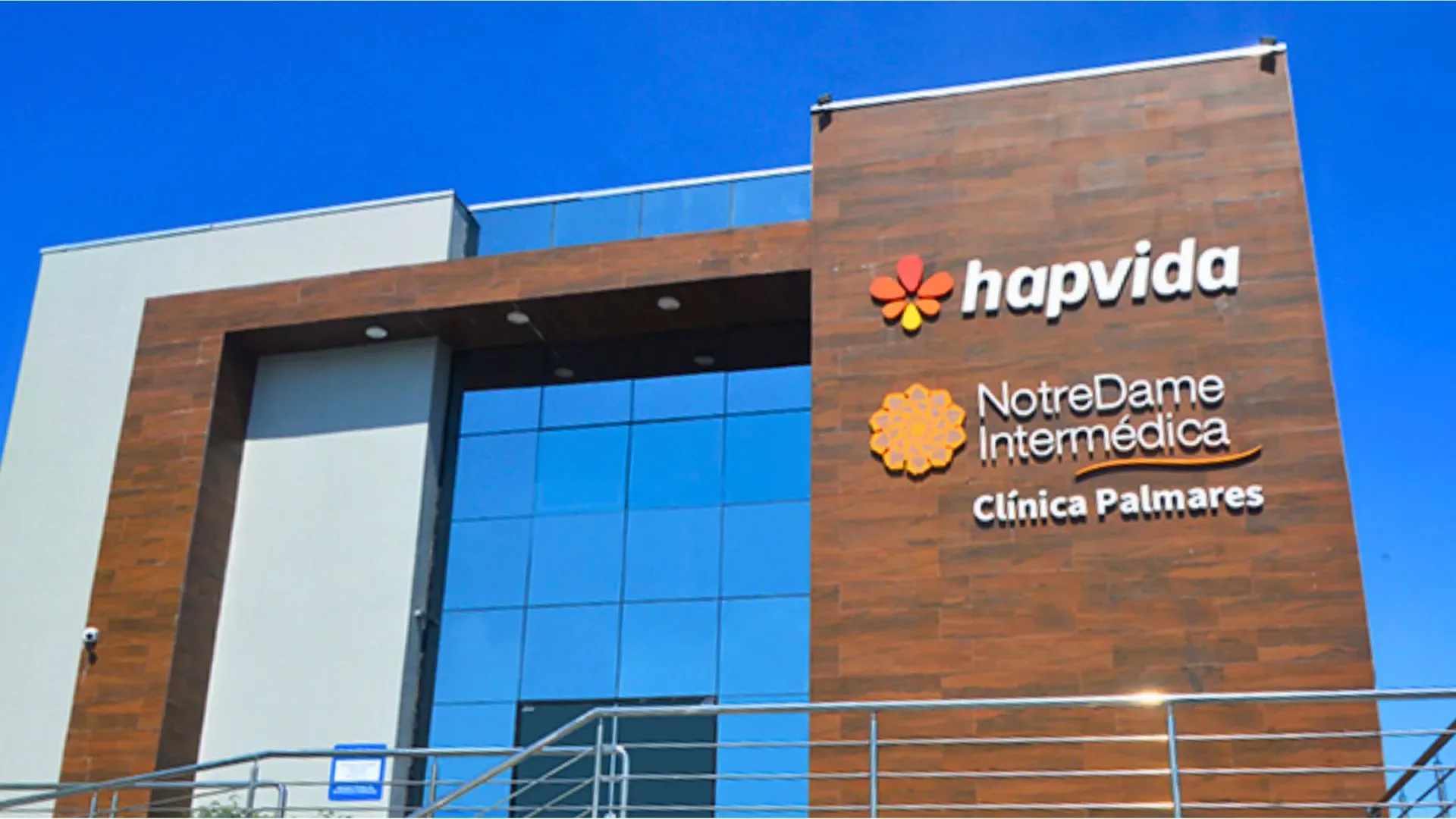 Fachada da unidade Hapvida sob céu azul, com a marca e slogan visíveis.