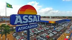 Fachada do Assaí Atacadista com o logotipo em destaque e estacionamento lotado, ideal para compras de atacado e varejo. Imagem ilustrativa de uma loja do Assaí Atacadista (ASAI3)