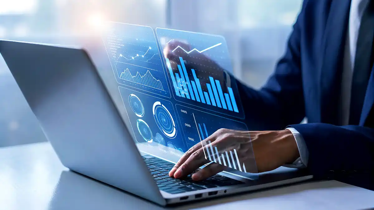 Homem de negócios digitando em um laptop que exibe gráficos de dados, machine learning e inteligência artificial, representando a Carteira Quant Experience.