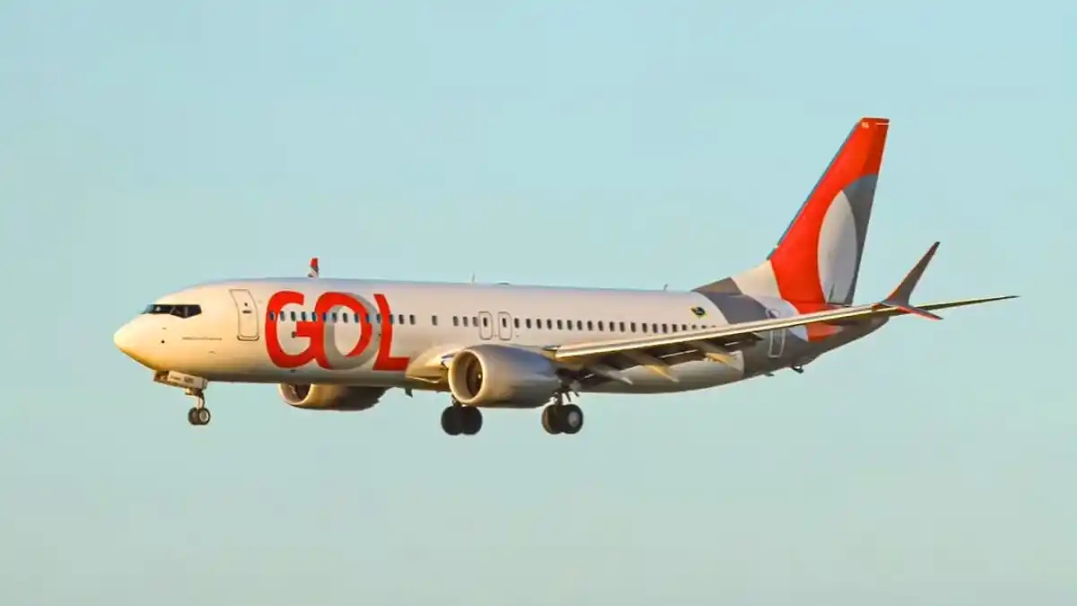 Avião da companhia aérea Gol em voo, com o logo em vermelho na fuselagem e na cauda, representando a controladora Abra.