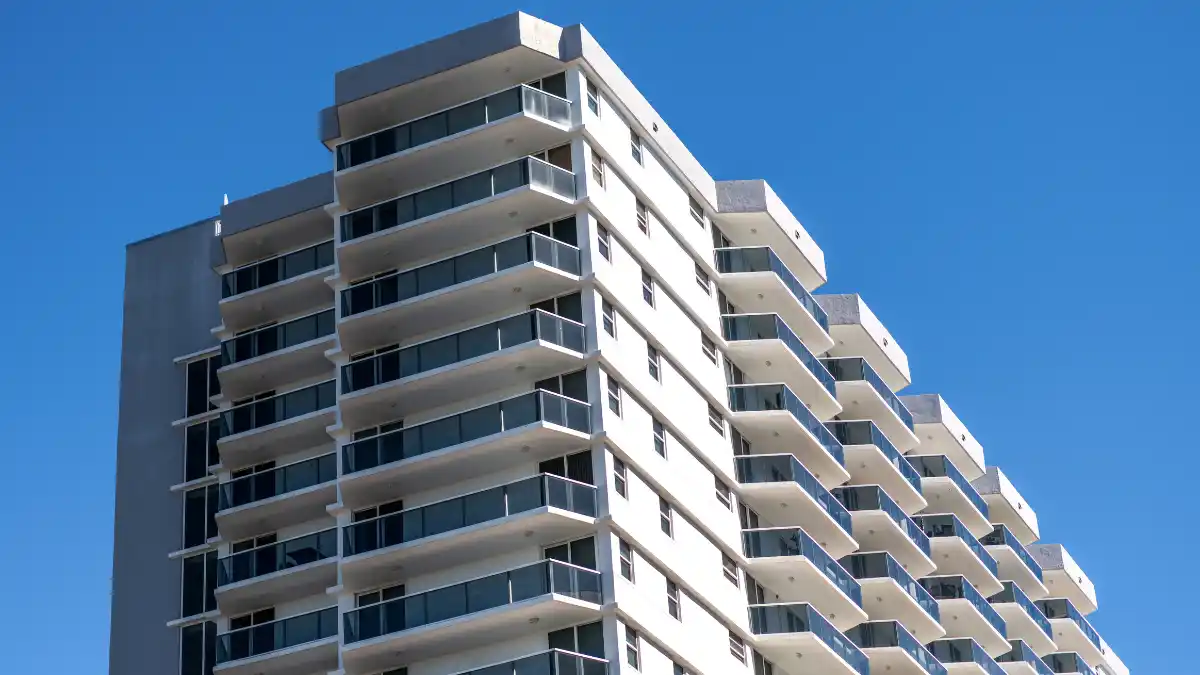 Prédio residencial moderno e de alto padrão, com múltiplas varandas e fachada de vidro, ilustrando a classe de ativos Private Real Estate.