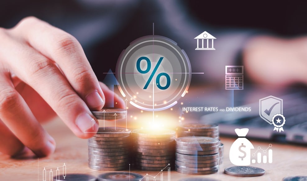 renda fixa em outubro: imagem de mão de homem analisando pilhas de moedas, enquanto ícones de investimento e proteção são projetados ao fundo