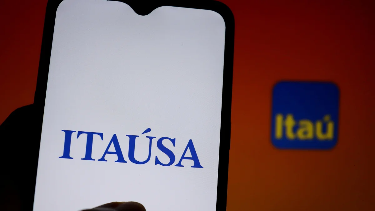 Tela de celular exibindo o logotipo da Itaúsa em destaque, simbolizando o anúncio de R$ 8,7 bilhões em proventos que fez a ação (ITSA4) disparar entre as mais negociadas.
