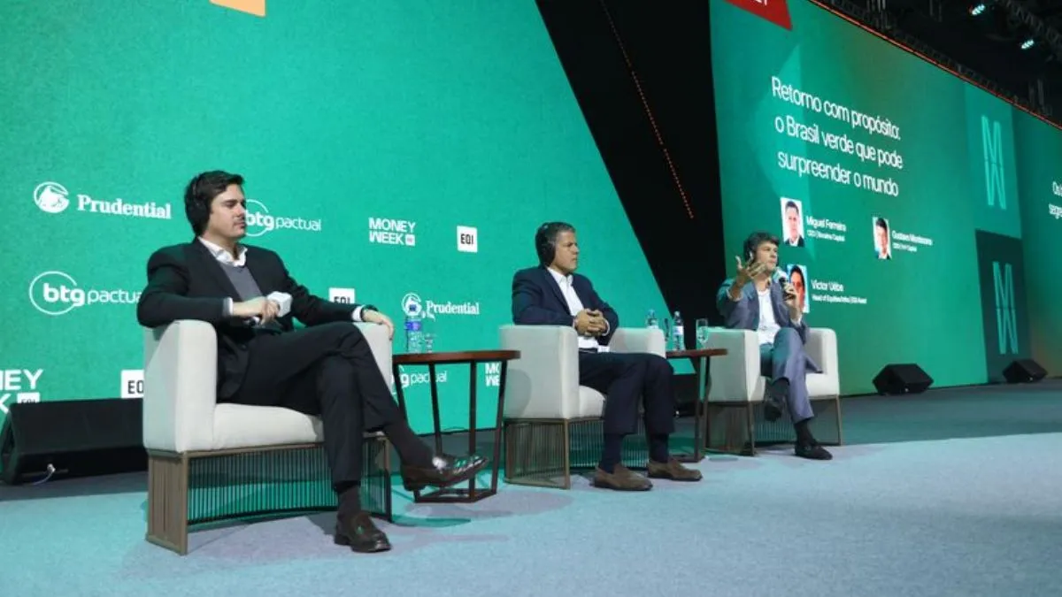 Painel da Money Week com três participantes sentados em sofás.