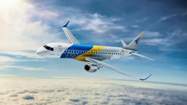 Avião comercial da Embraer com pintura nas cores do Brasil em voo, simbolizando a volta da empresa ao rol das pagadoras de dividendos e a disparada da ação (EMBJ3) no pregão.