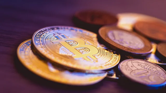 Moedas de Bitcoin douradas e prateadas empilhadas ao lado de moedas de Real (BRL), simbolizando a adoção de cripto no Brasil e a economia híbrida.