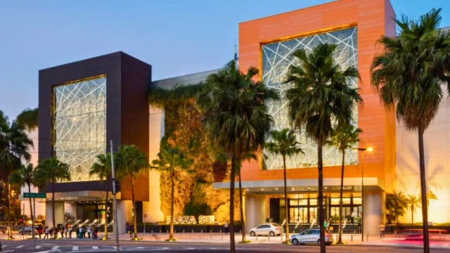 Vista panorâmica do interior de um shopping da Allos, com múltiplos andares, corredores circulares, claraboia de vidro no teto e pessoas circulando, ilustrando o recorde de allos ebtida.