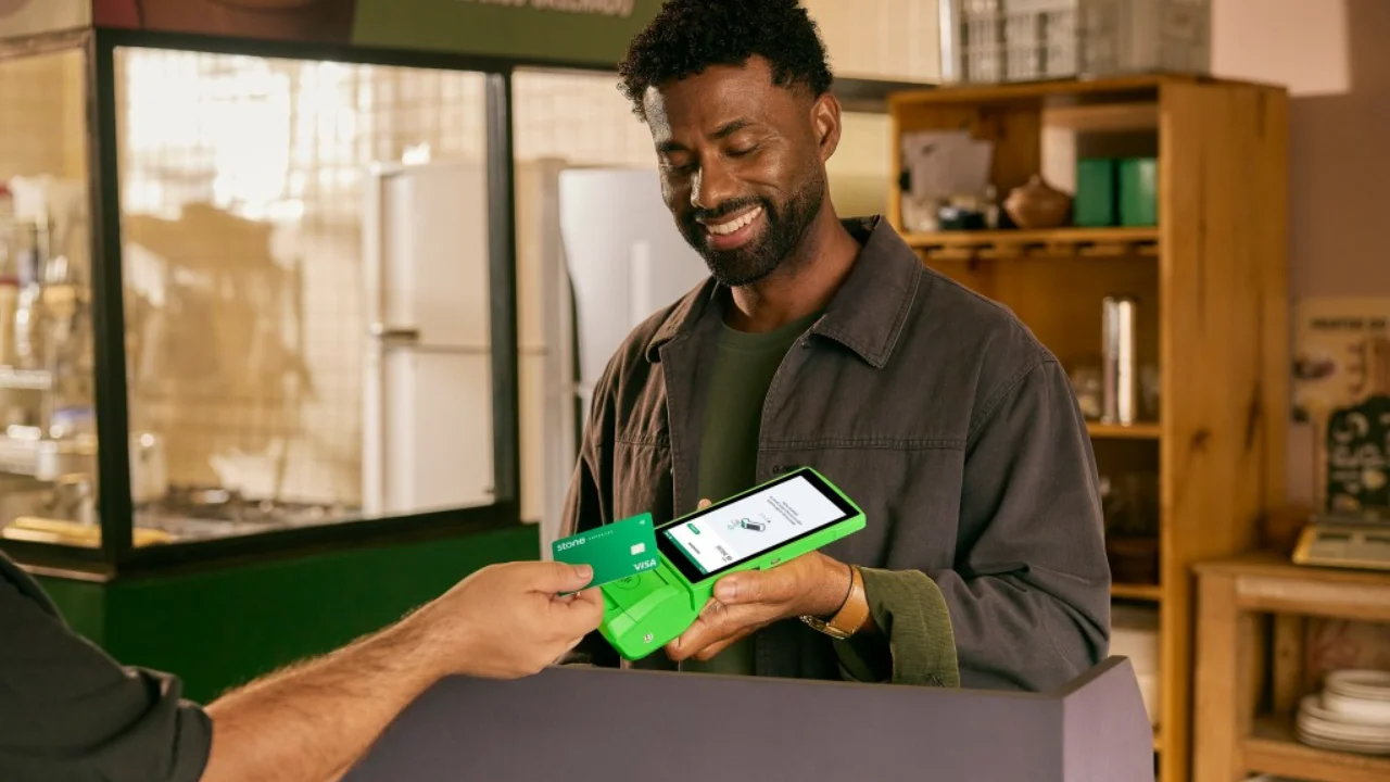 Homem recebendo pagamento de cartão em uma máquina da Stone
