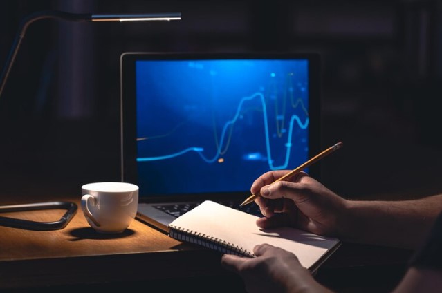 day trading: foto de homem anotando dados de gráfico para análise técnica de ações