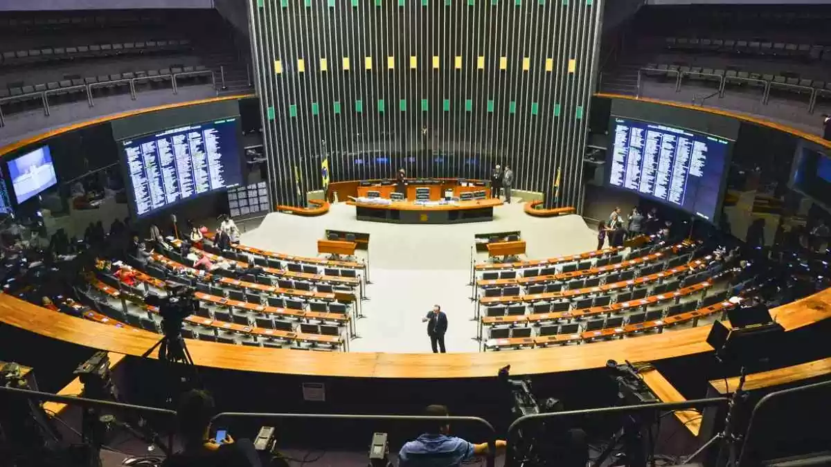 Vista panorâmica e superior do plenário da Câmara dos Deputados em Brasília, durante uma sessão de votação.